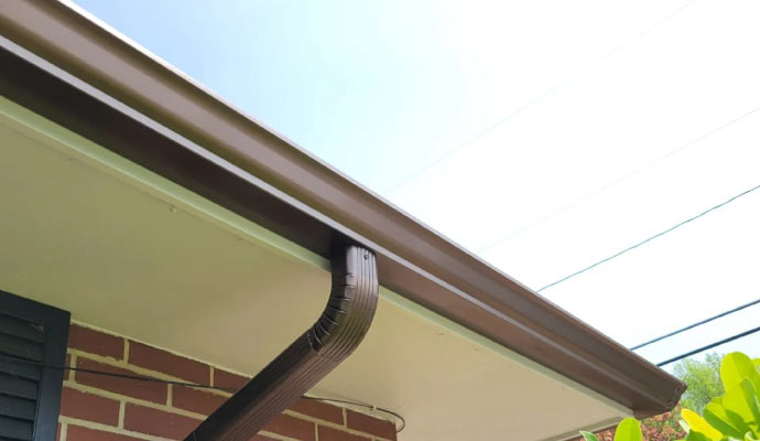 A clean bright gutter attached to a house roof