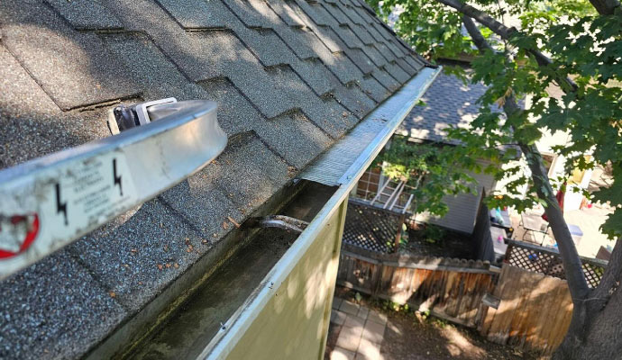 A house's roof and gutter being inspected