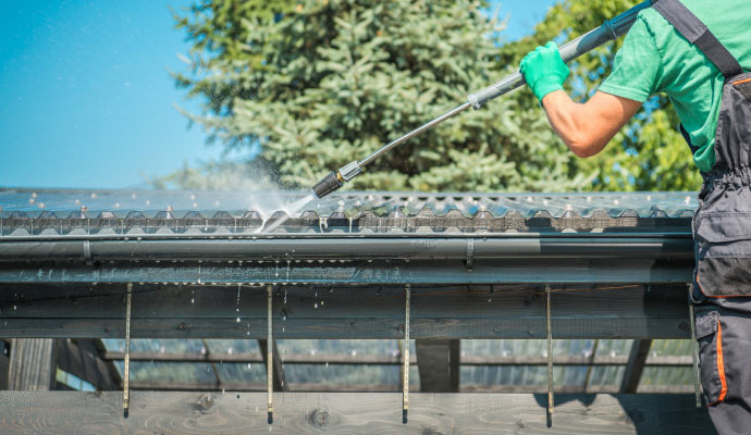 A person power washing a gutter