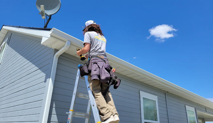 A person installing a gutter on a roof using equipment