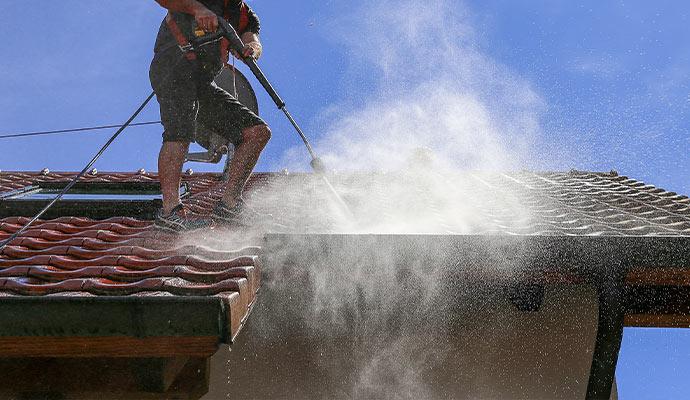 A man is powerwashing roof gutter