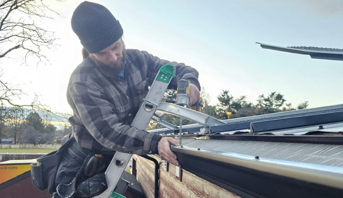 A person installing a gutter guard on a roof