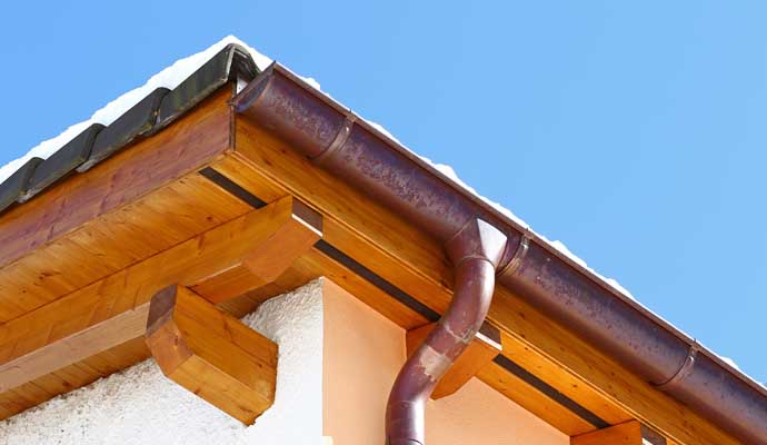 A section of a building's roof with a copper gutter system installed.