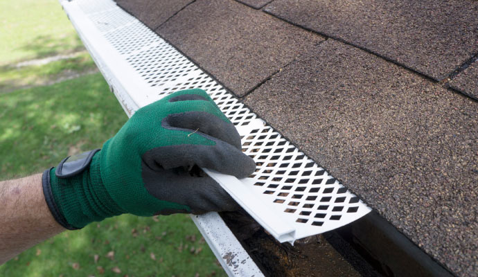 Person installing gutter guard with equipment