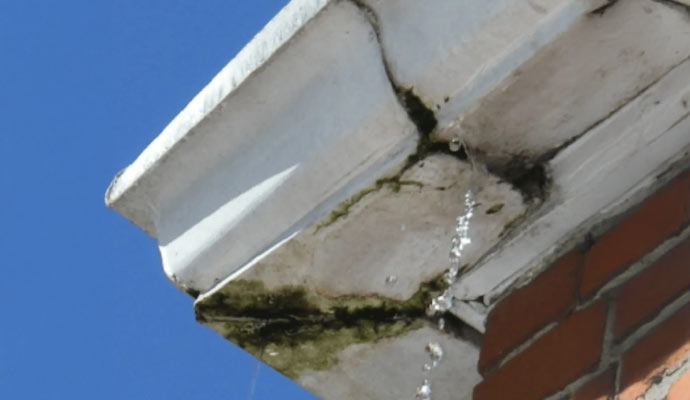 A gutter with water leaking from a crack