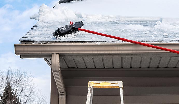 Snow removal from gutters by a worker in the Boise Area